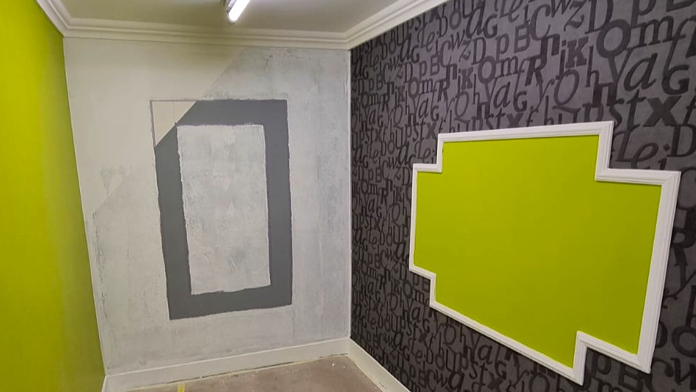 Préparation des murs avant peinture avec zone poncée et tracée, et tapisserie grise à motifs avec cadre décoratif vert